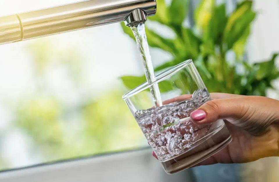 Main remplissant un verre d'eau au robinet