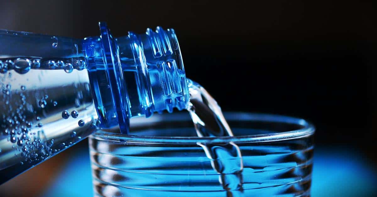 bouteille d'eau en plastique remplissant un verre