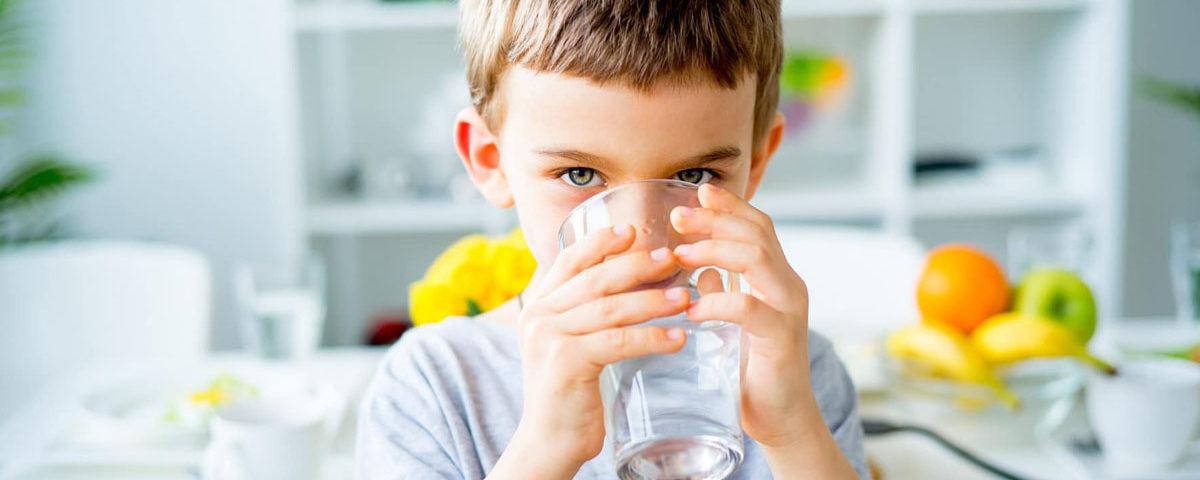 Enfant qui boit un grand verre d'eau