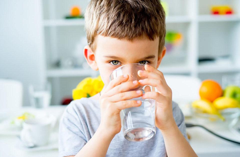 Enfant qui boit un grand verre d'eau