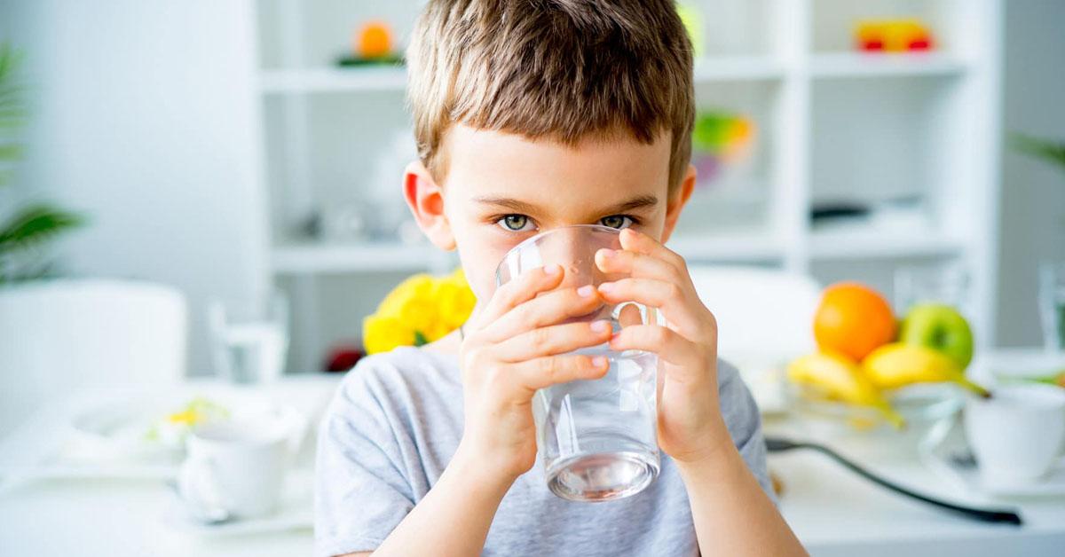 Enfant qui boit un grand verre d'eau