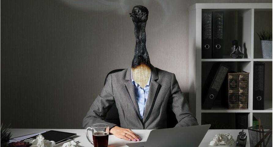 Employé assis à son bureau avec une allumette grillée à la place de la tête