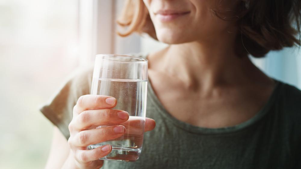 Femme tenant un verre d'eau